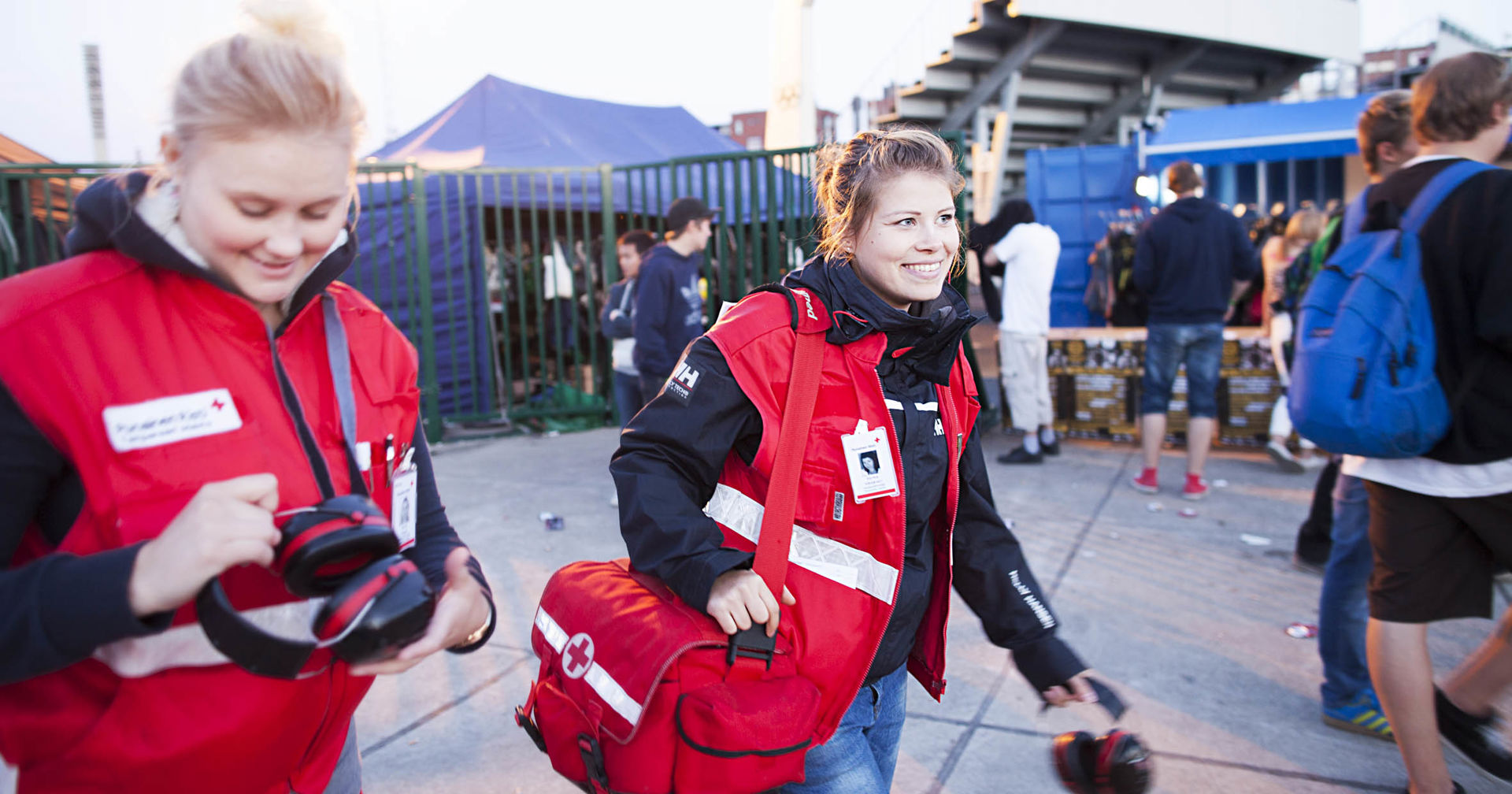 Två personer klädda i Röda Korsets västar går utomhus.