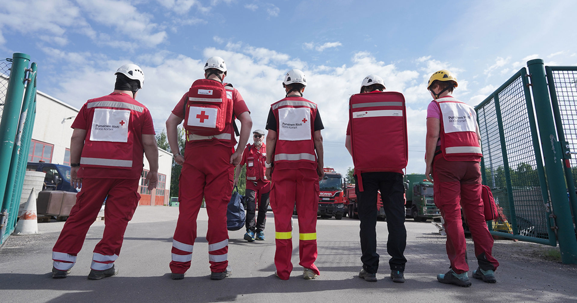 Fem frivilliga från Röda Korset står på rad. Alla har frivilligvästar på sig.
