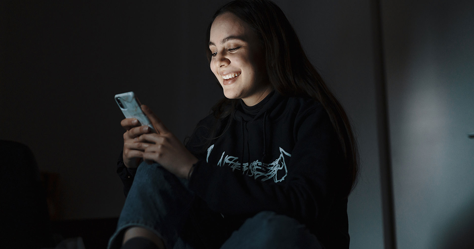 En person tittar på sin telefon och ler.