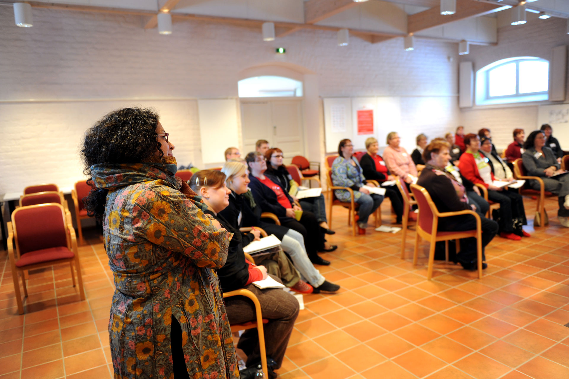 Människor sitter i ett klassrum i en halvcirkel.