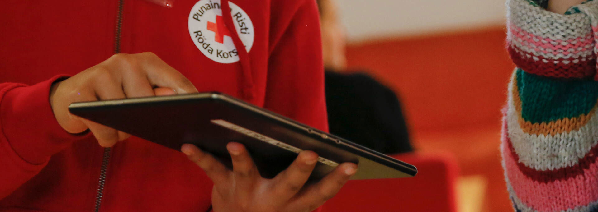 En person håller i en surfplatta och visar den för en annan.