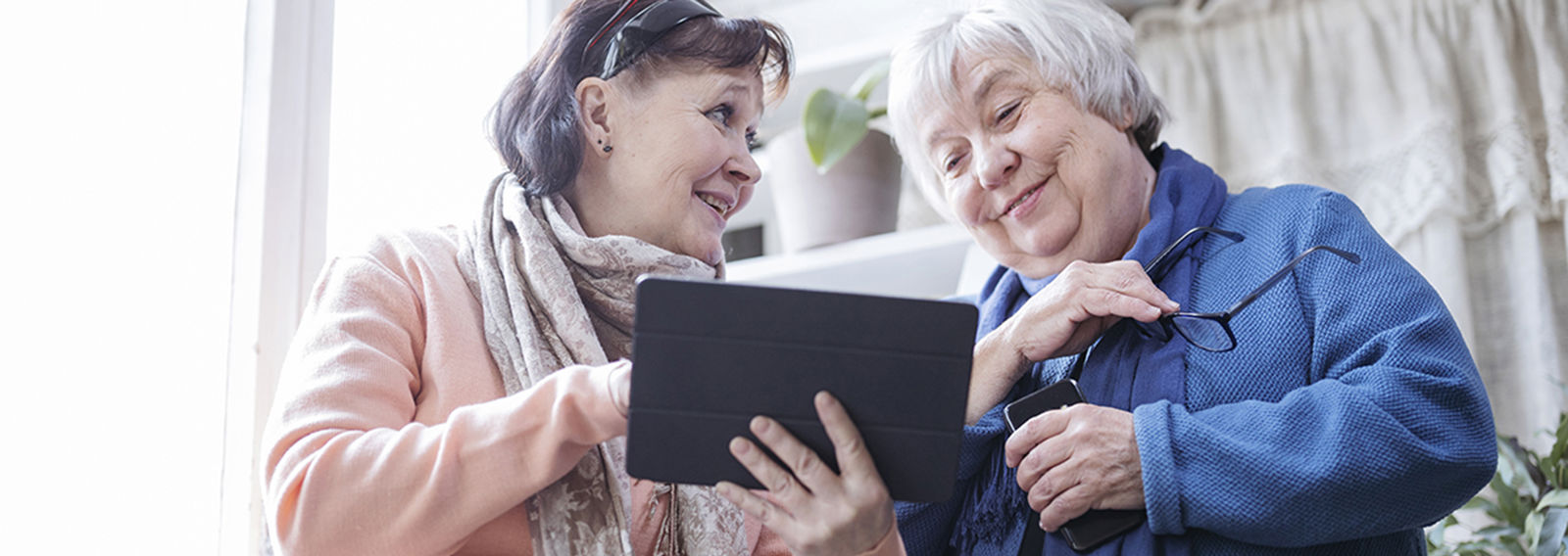 Två personer tittar tillsammans på en surfplatta och ler mot varandra.