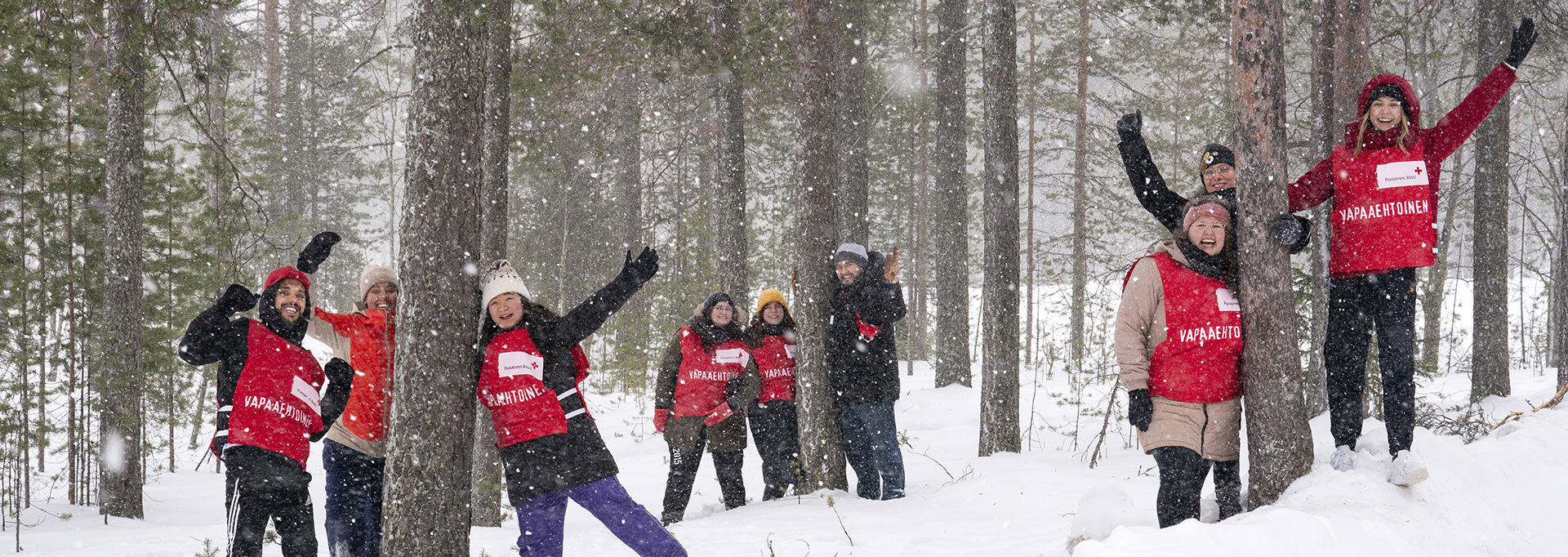 En grupp frivilliga vinkar mot kameran i en snöig terräng.