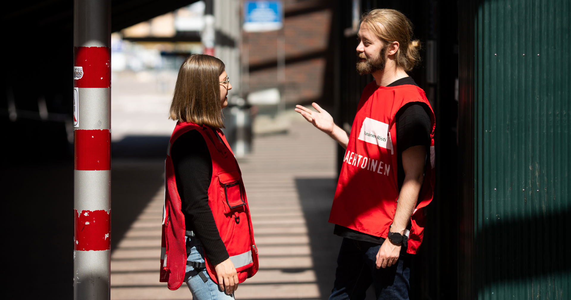 Två frivilliga från Finlands Röda Kors samtalar i solskenet.