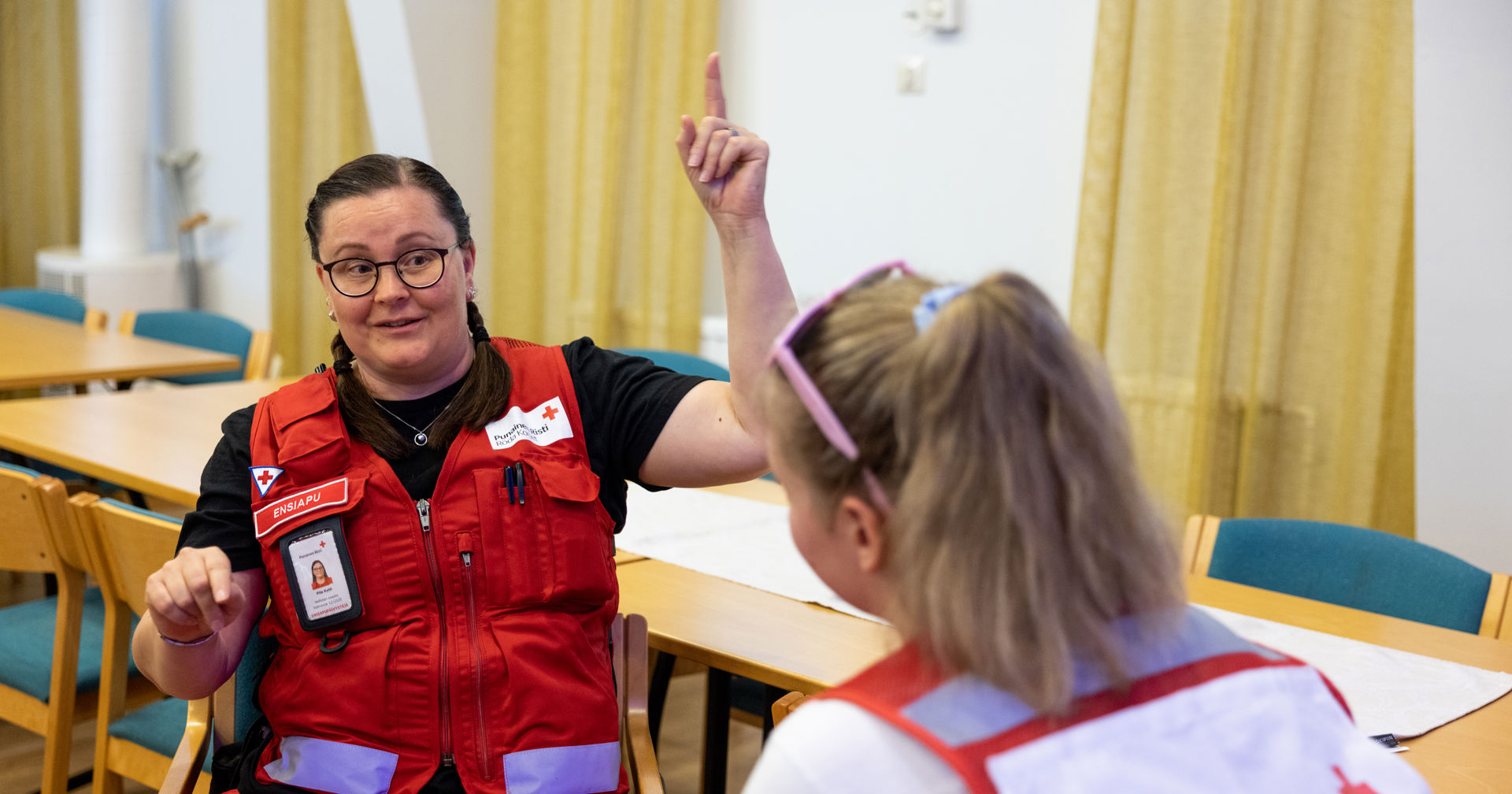 Två frivilliga från Finlands Röda Kors samtalar under en ledarskapsutbildning. Den ena pekar uppåt med handen.