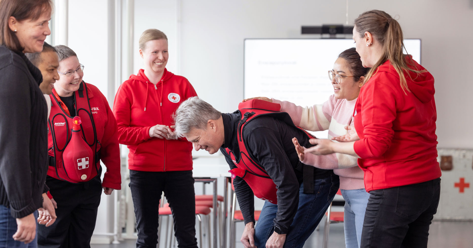 Frivilliga leende i en ring. En person lutar sig framåt i mitten.