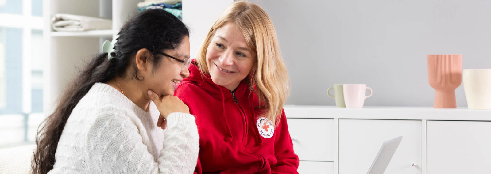 En frivillig guidar en nyanställd på avdelningen, som har en dator i knät.