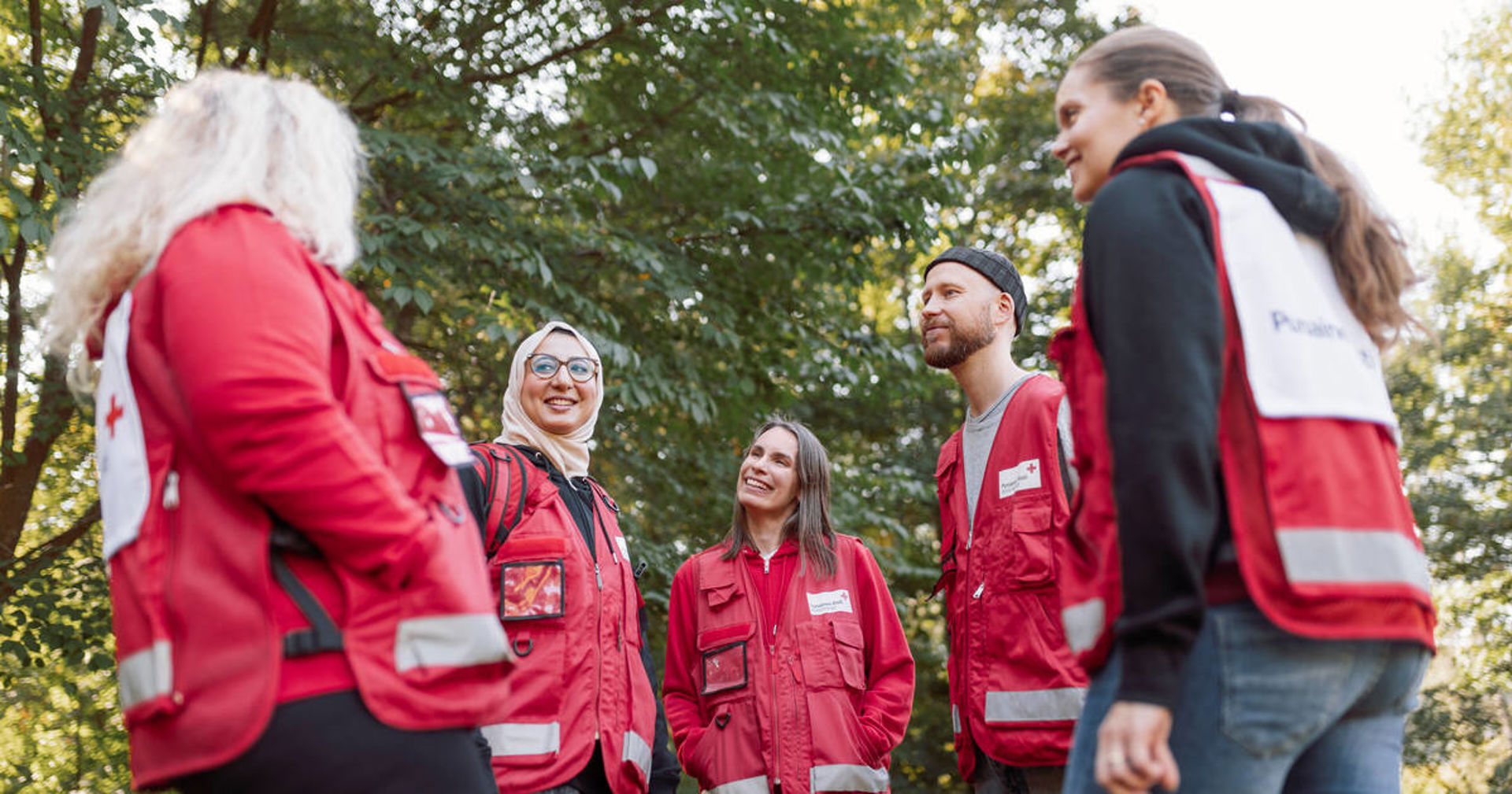 En grupp frivilliga diskuterar. Alla har på sig Röda Korsets frivilligvästar.