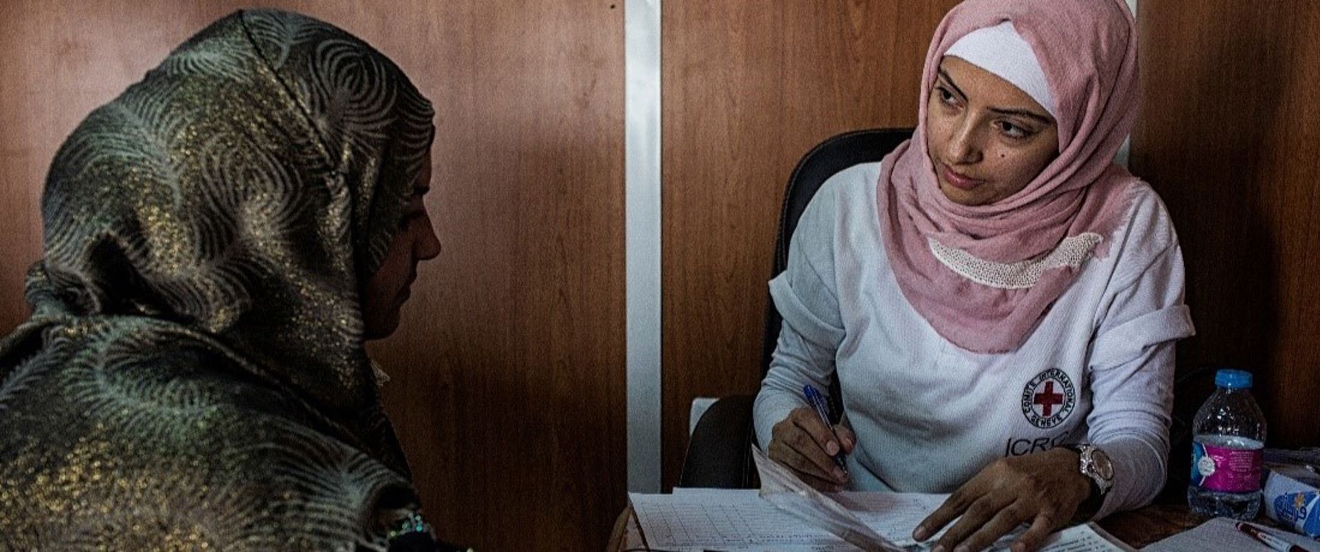 En anställd vid Röda Korset samtalar med en person och för anteckningar.