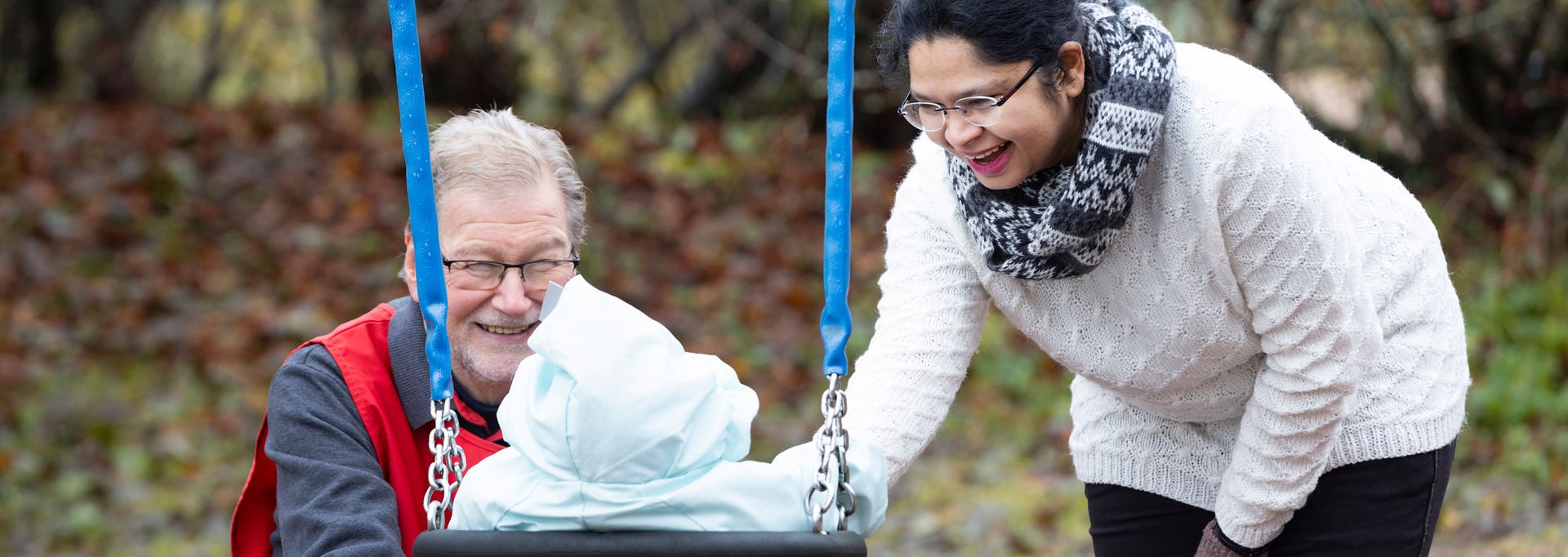 Röda Korsets frivillig och en person skjuter på ett barn i en gunga.