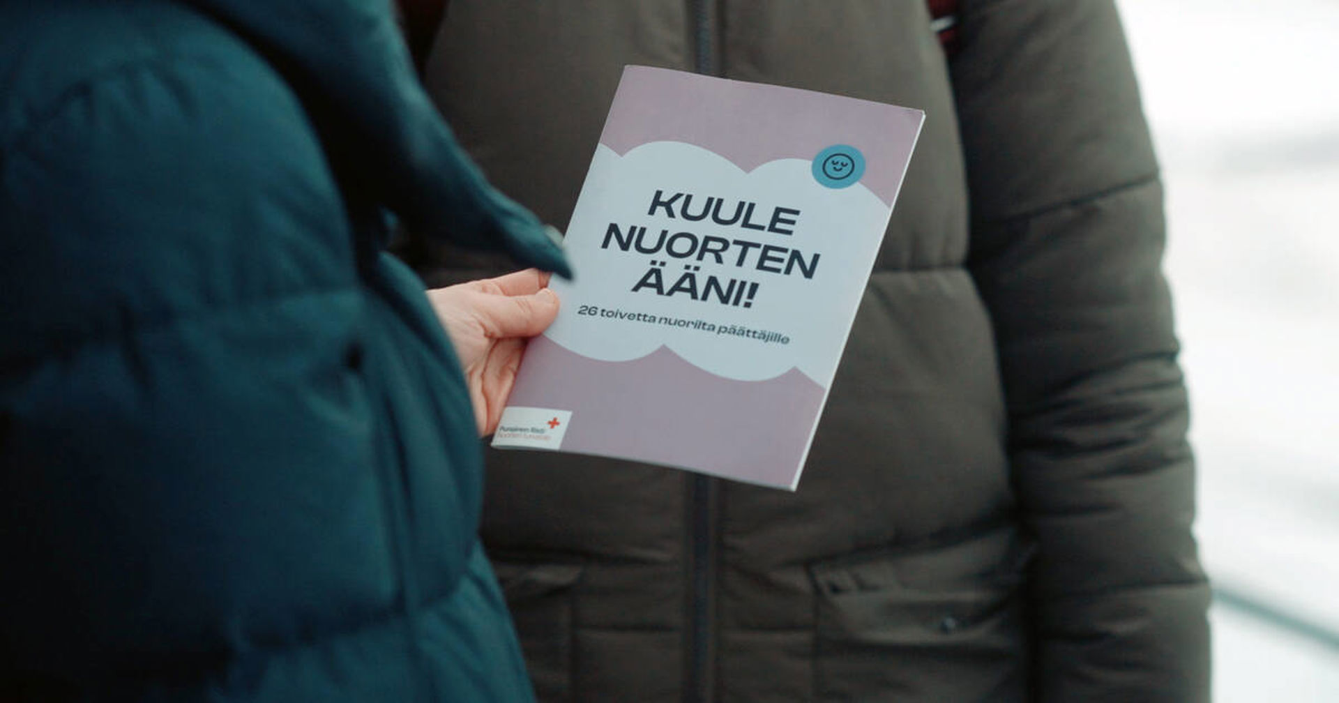 Två personer, varav den ena håller i publikationen Hör de ungas röst!.