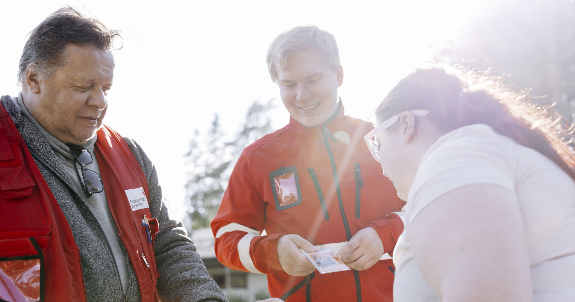 Finlands Röda Kors frivilliga inom rusmedelsarbete erbjuder broschyrer till en ung person.