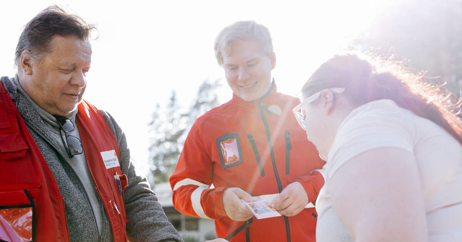 Två av Röda Korsets frivilliga pratar med en ung person.
