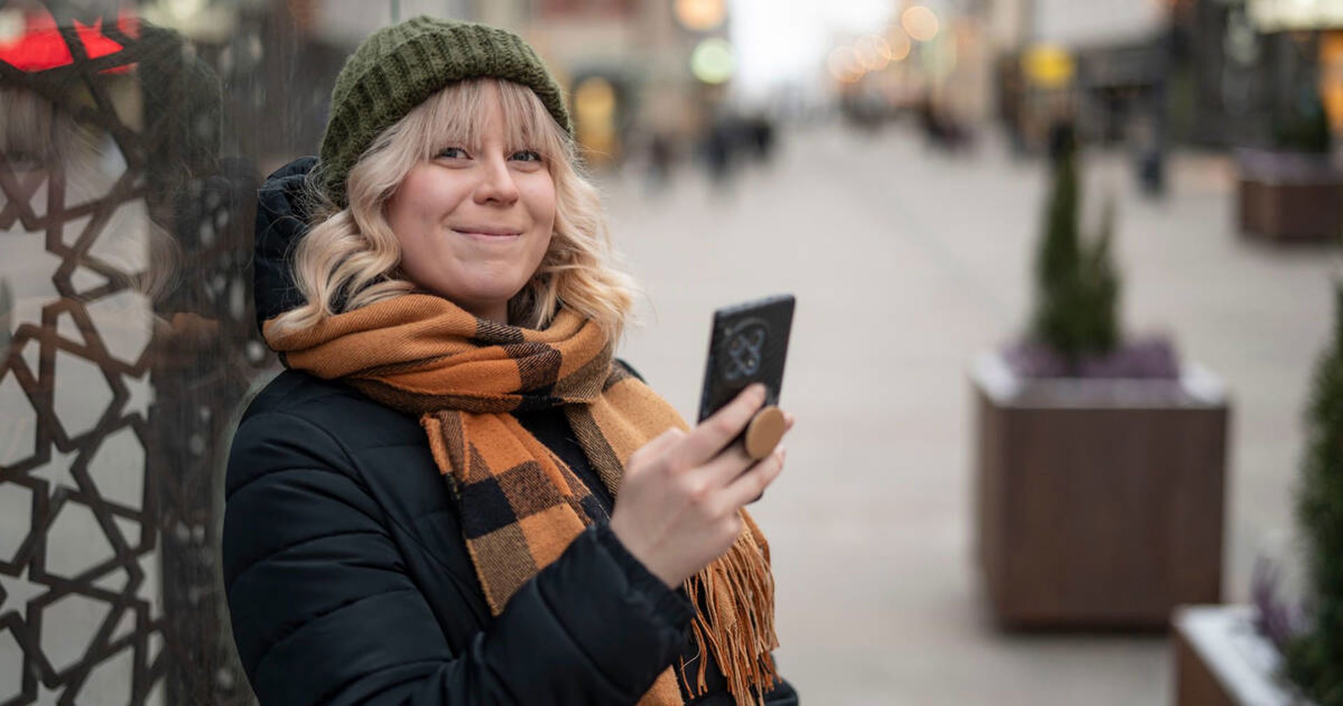 En person ler med en telefon i handen.