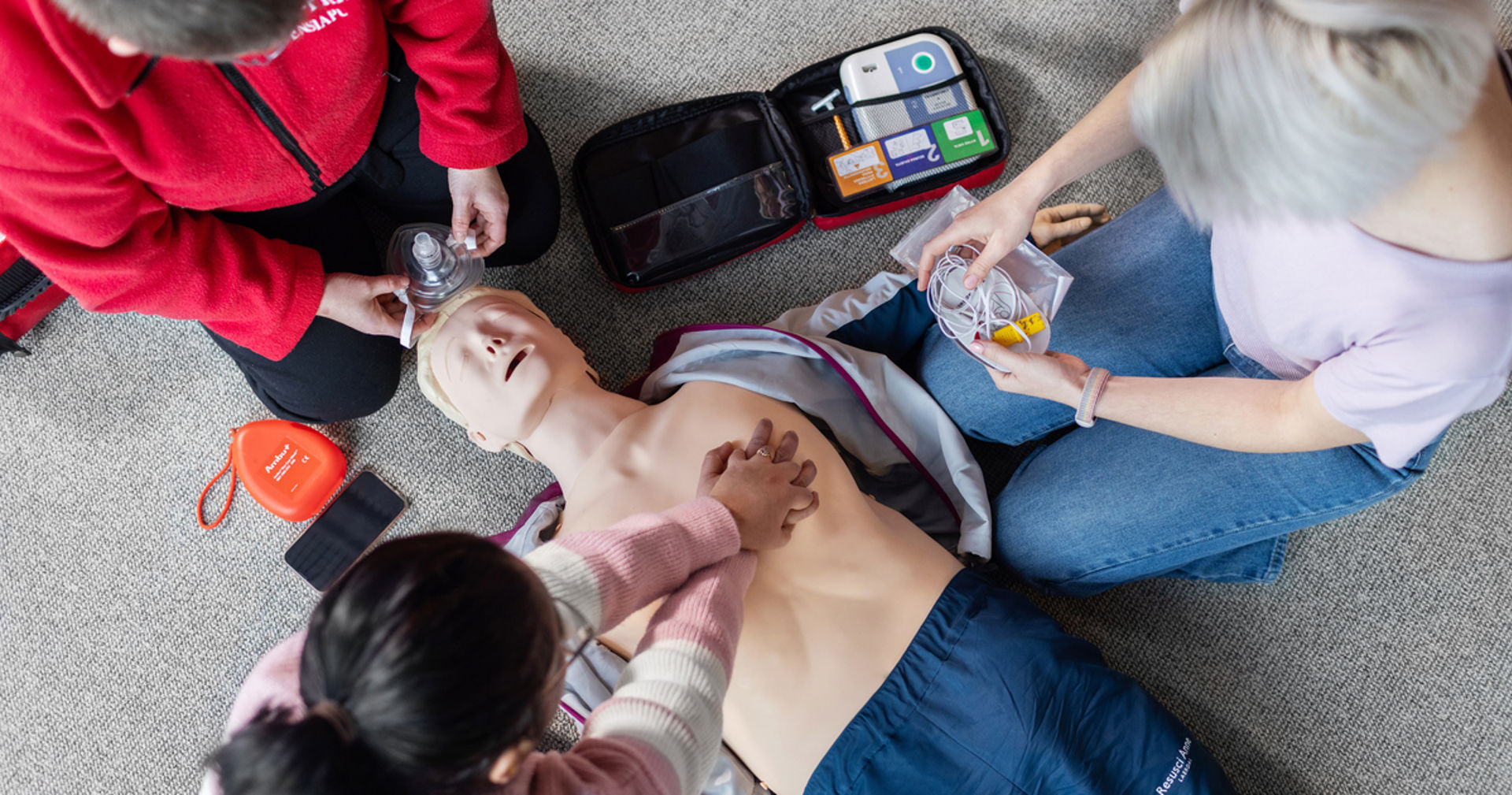 Tre personer runt en hlr-docka.