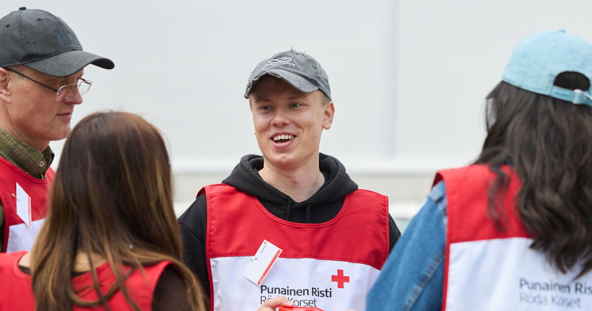 En grupp på fyra personer samtalar utomhus iklädda insamlingsvästar.