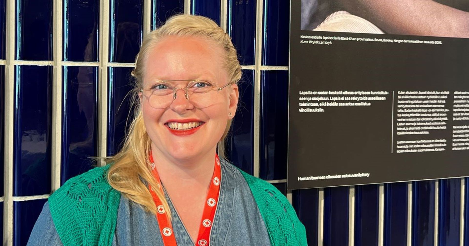 En person ler mot kameran vid Röda Korsets ordinarie stämma, med ett rött evenemangslanyard runt halsen.