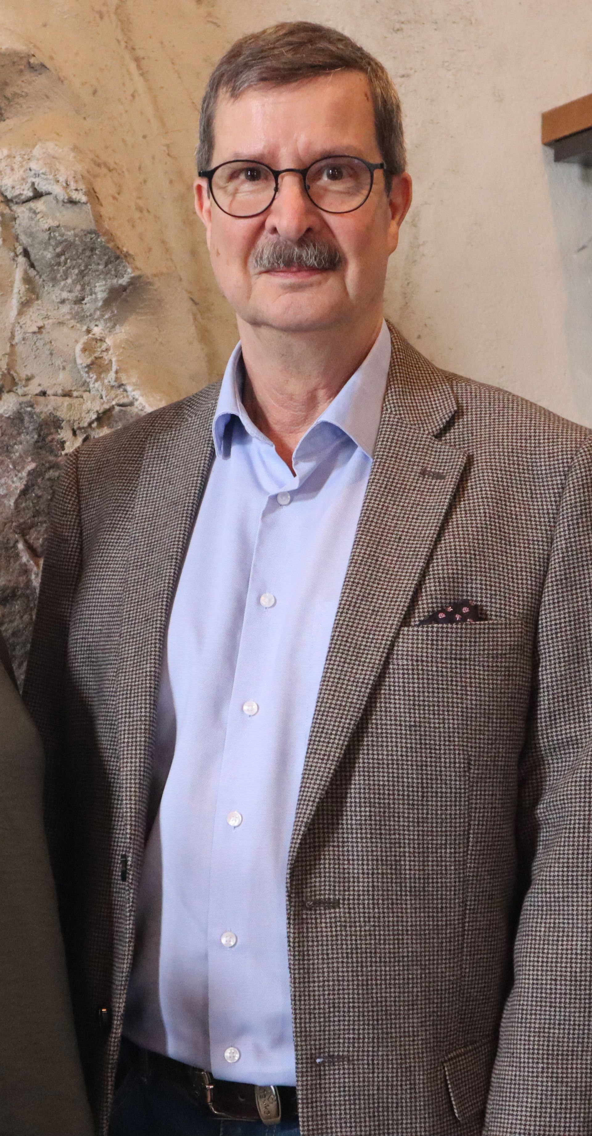 Kenneth Nygård tittar mot kameran, klädd i en ljus skjorta och en brunaktig kavaj.