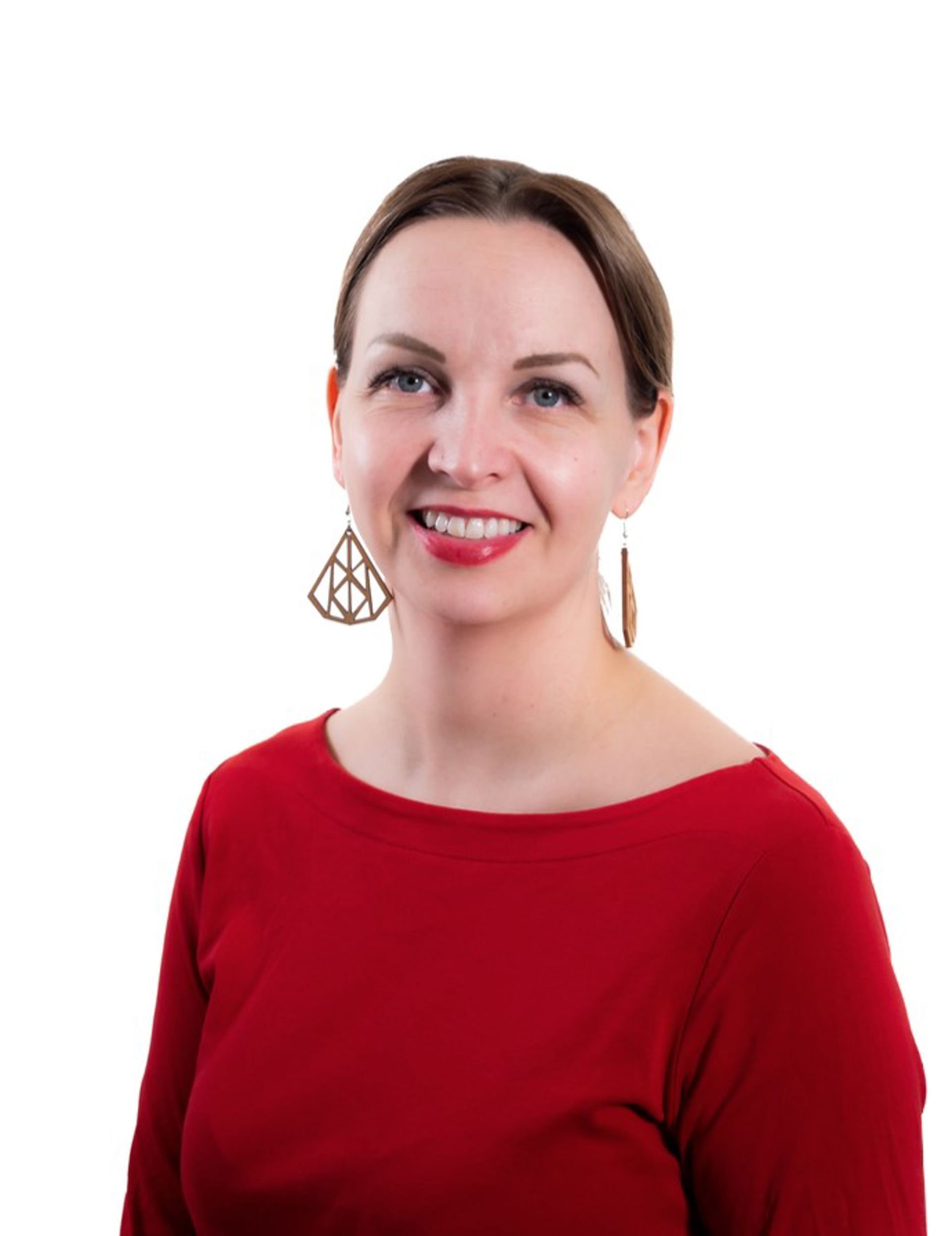 Maarit Villman tittar mot kameran, klädd i en röd tröja och stora örhängen.