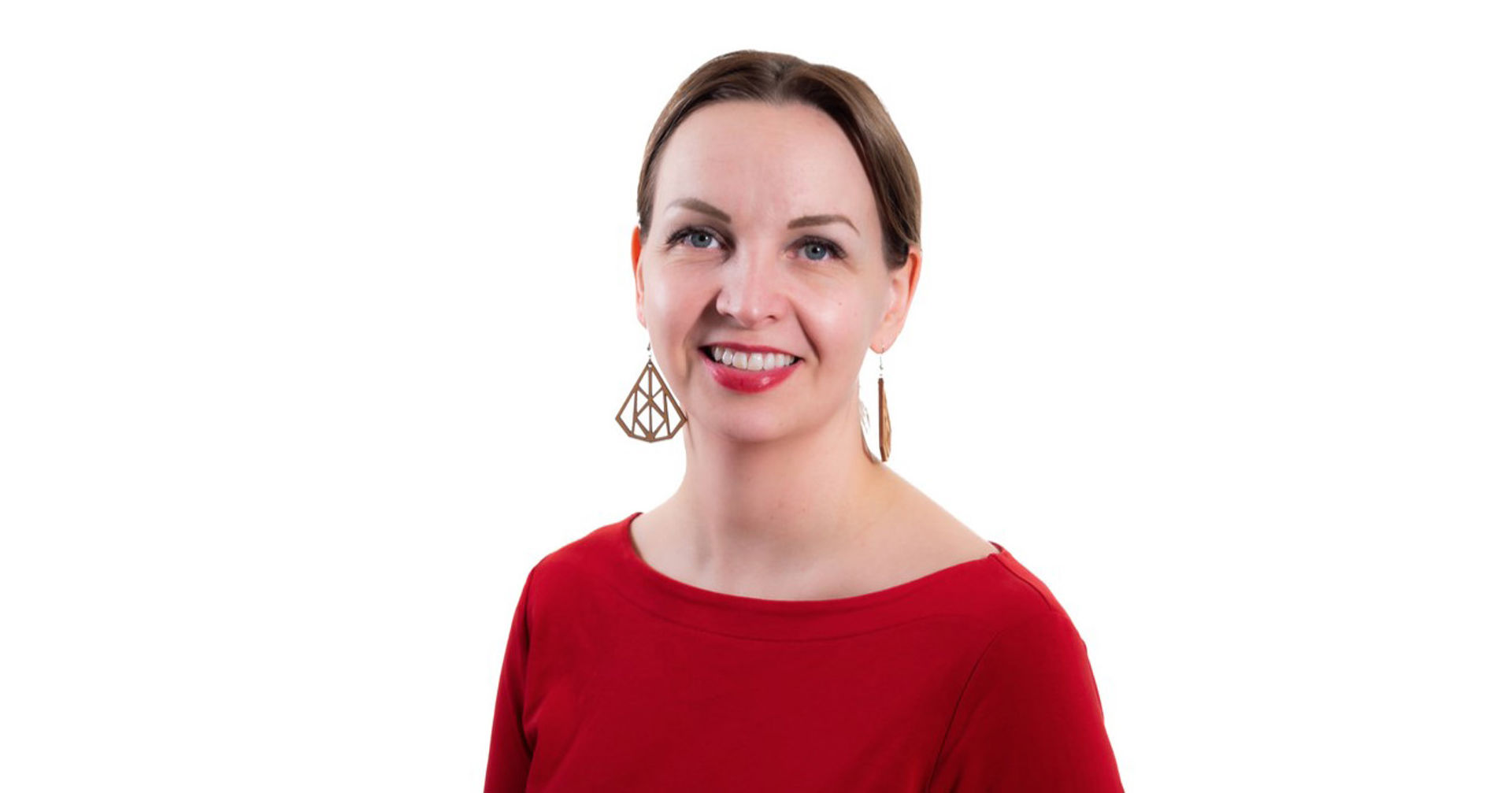 Maarit Villman tittar mot kameran, klädd i en röd tröja och stora örhängen.