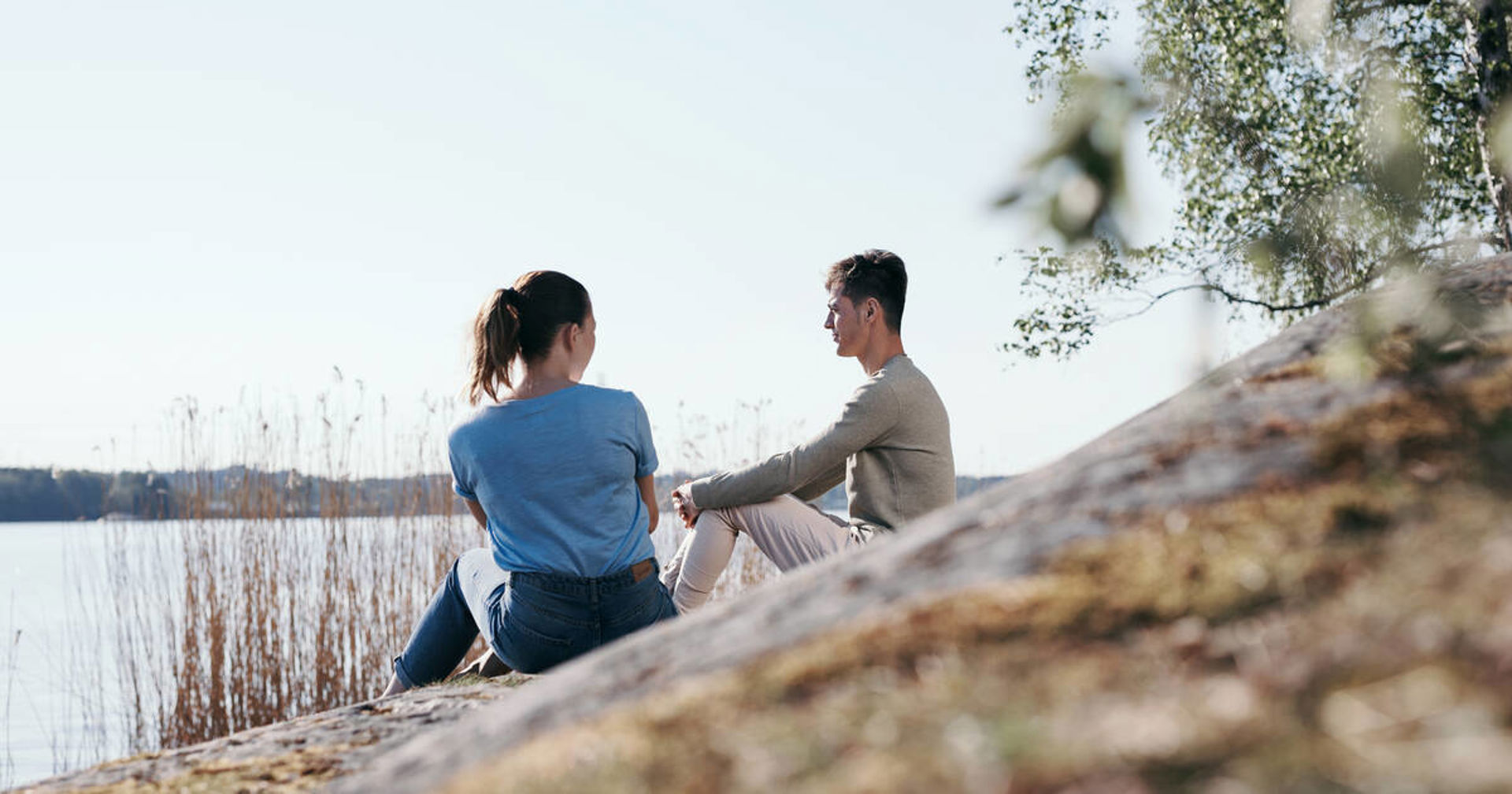 Två personer pratar på klipporna vid stranden.