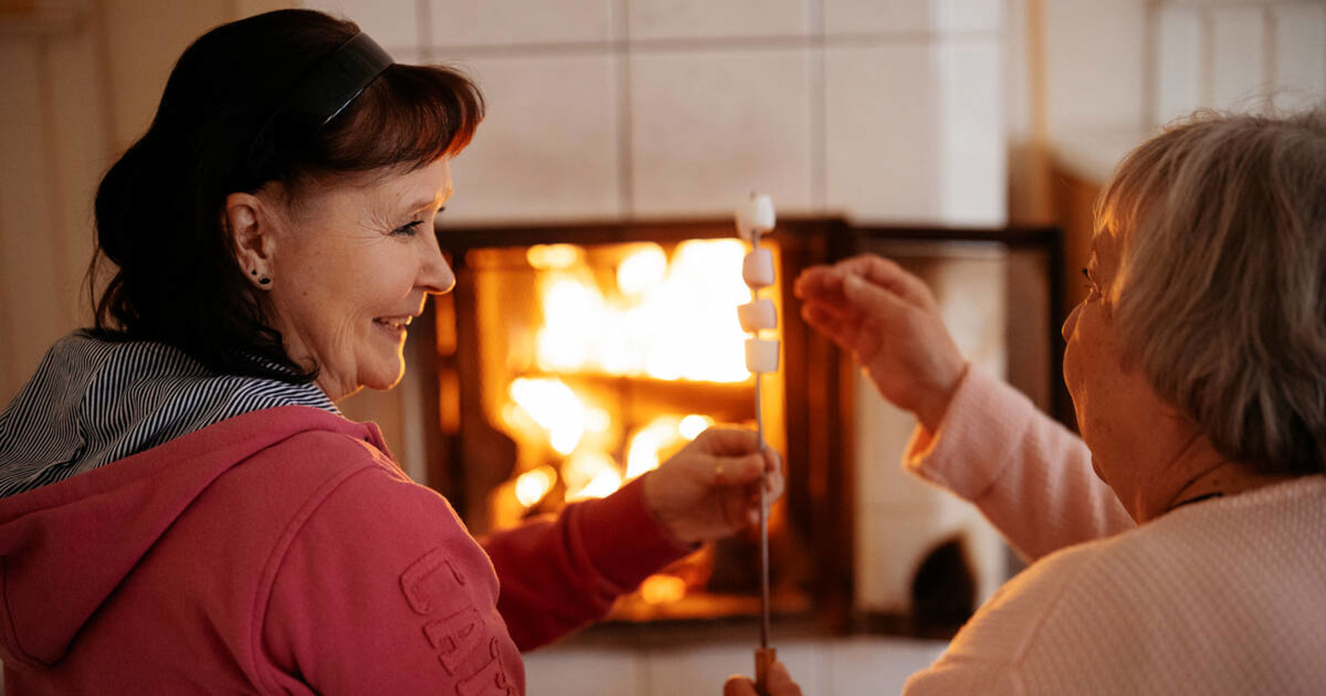 Två personer rostar marshmallows i den öppna spisen.
