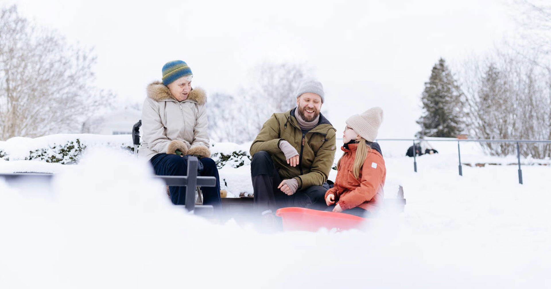 Familj i pulkabacken i ett snöigt landskap.