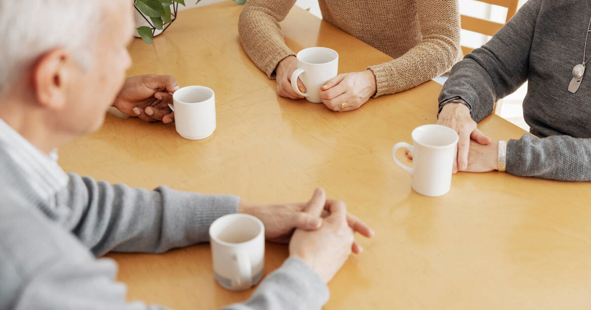 Fyra par händer och kaffekoppar på bordet.